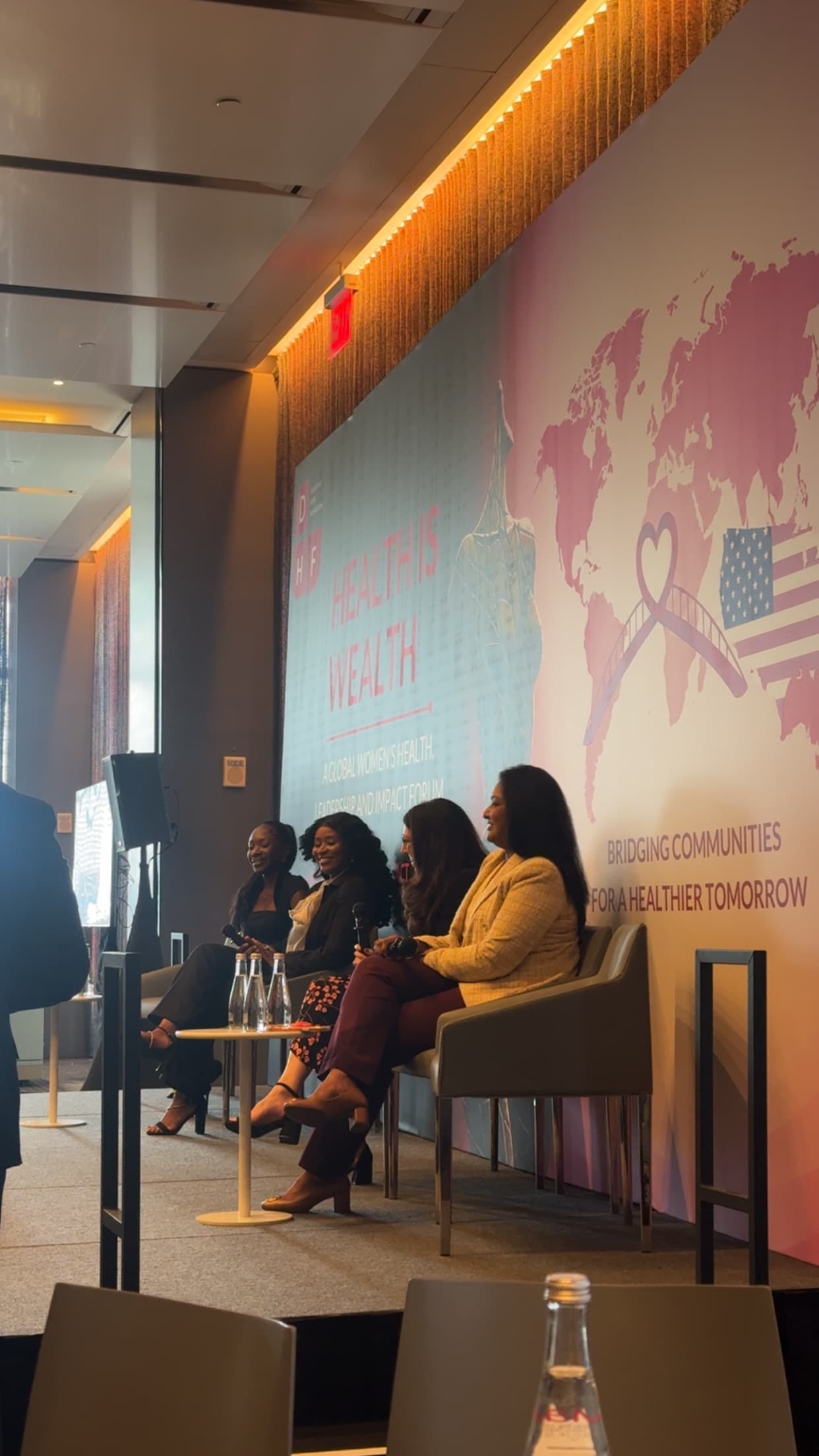 Panelists seated on stage at the Health Is Wealth forum, in front of a Dorothy’s Hope Foundation banner.