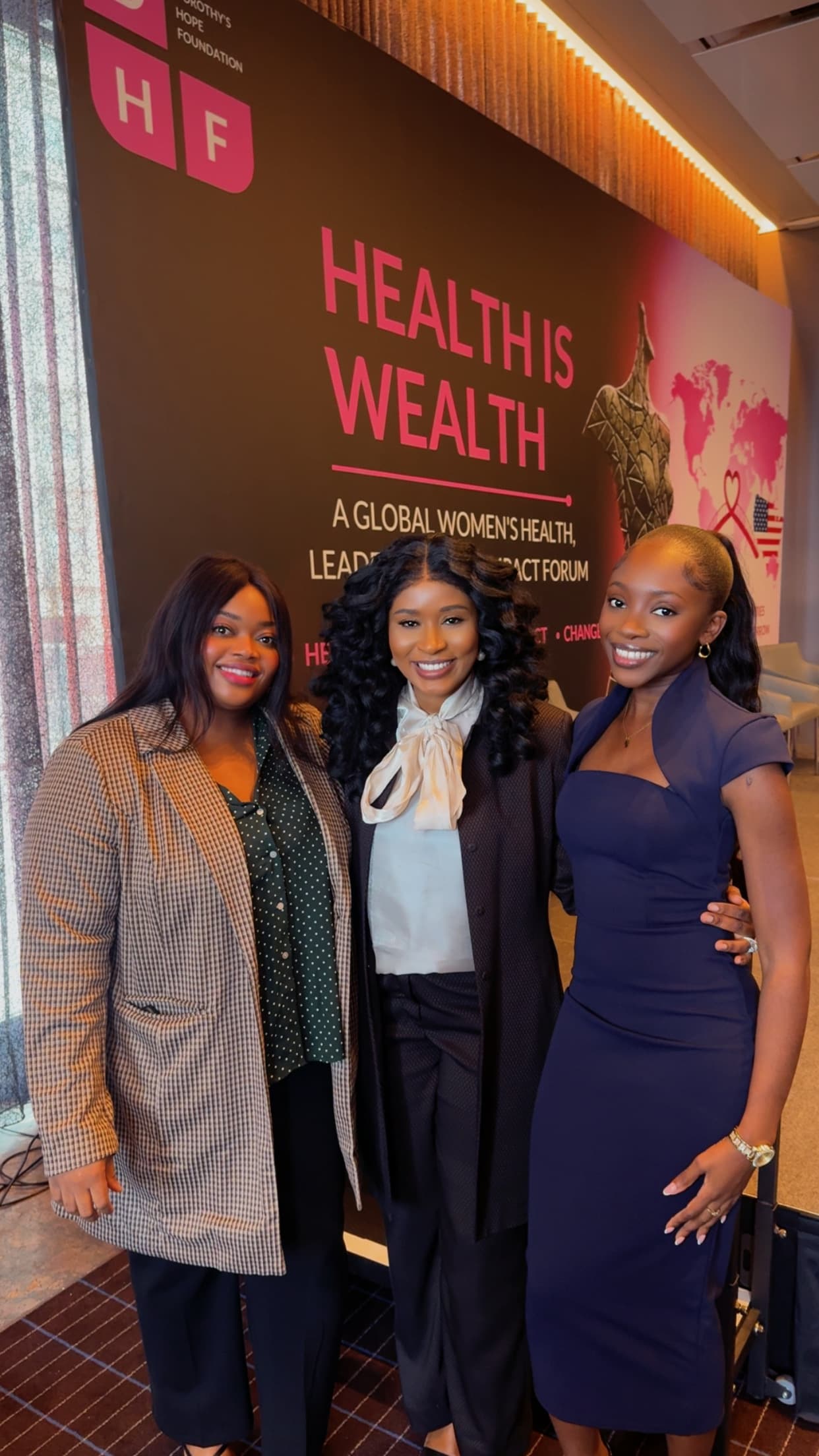 Three attendees pose in front of the Health Is Wealth backdrop at the Dorothy’s Hope Foundation forum.