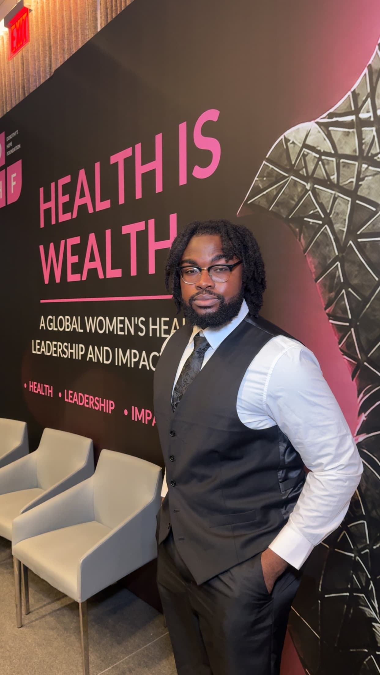 An attendee stands in front of the Health Is Wealth backdrop at the Dorothy’s Hope Foundation forum.