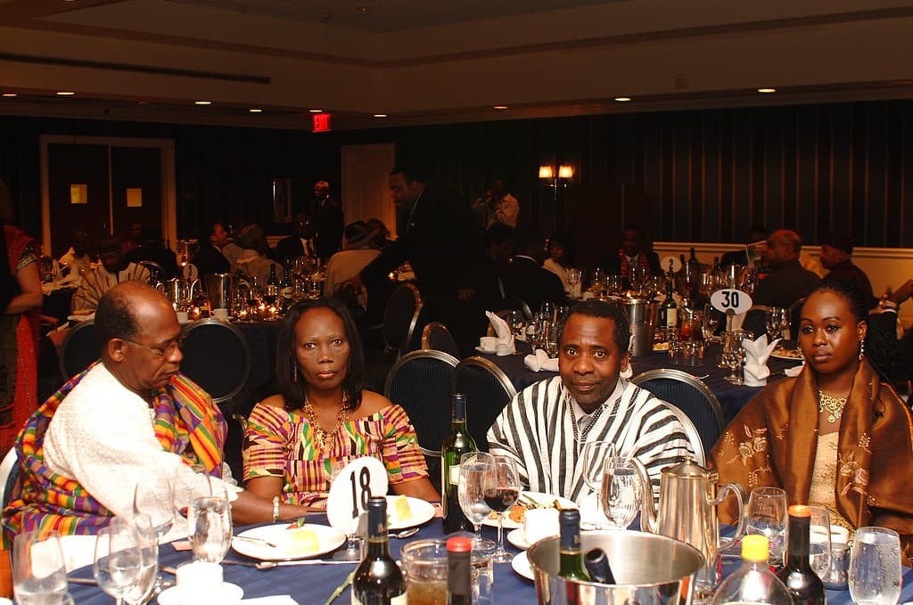 People seated together at banquet tables, some wearing Ghanaian cloth.